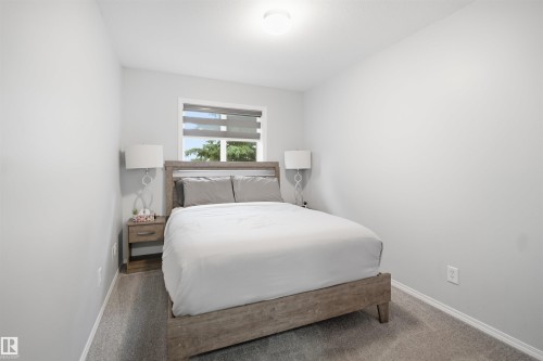 Bedroom featuring light gray wall paint, gray carpet flooring, a window with horizontal blinds, and a flush mount ceiling light fixture - 92 230 Edwards Drive, Edmonton, AB 