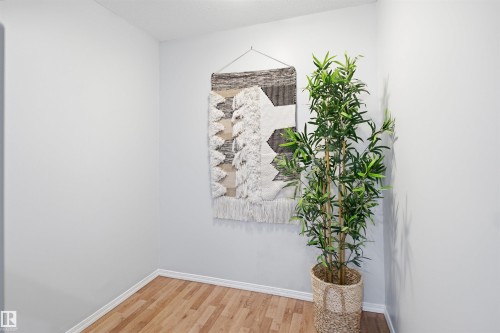 Light wood-finish flooring with white baseboards and light-toned walls create a neutral palette - 92 230 Edwards Drive, Edmonton, AB 