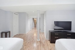 Spacious lower-level room featuring wood-finish flooring, light gray walls, and white trim - 