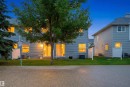 Rear exterior featuring light grey siding, multiple windows, a sliding glass door, and white privacy fencing - 92 230 Edwards Drive, Edmonton, AB 