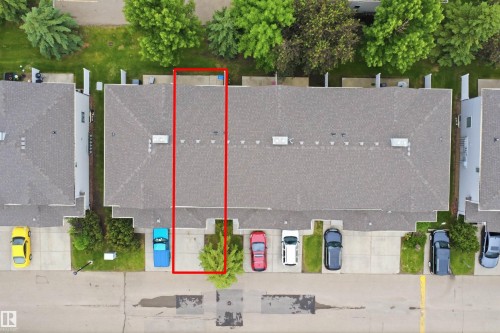 Townhome property featuring a gray shingle roof, rear patio space, and a front parking pad - 92 230 Edwards Drive, Edmonton, AB 