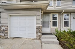 Exterior facade featuring horizontal siding, a white panel garage door, and a stone veneer foundation accent - 