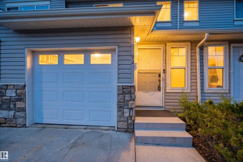 Inviting entry featuring a covered porch, concrete steps, and a garage with window inserts - 92 230 Edwards Drive, Edmonton, AB 