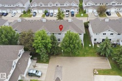 Townhome community featuring gray siding, dark shingle roofs, mature trees, and individual parking areas - 