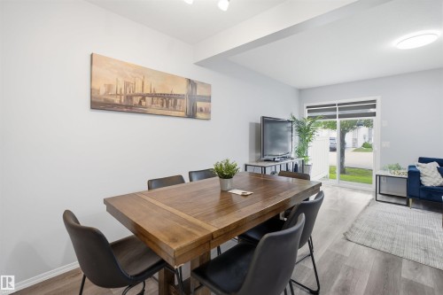 Dining area featuring wood-finish flooring, a contemporary overhead light fixture, and a sliding glass door providing exterior access - 92 230 Edwards Drive, Edmonton, AB 