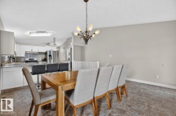 Open concept dining area featuring a decorative chandelier, tile flooring, and light gray walls - 