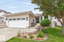 Cream-colored siding exterior featuring a multi-pane garage door, bay windows, and a black front door - 448 Ormsby Road W, Edmonton, AB 