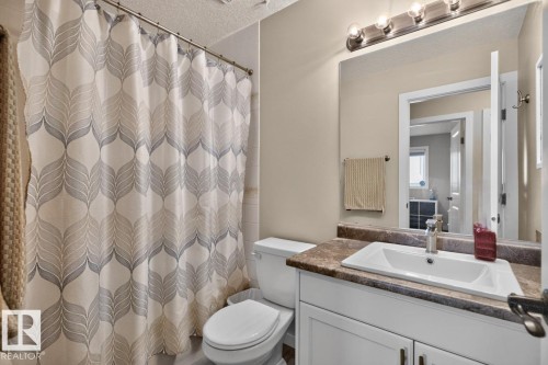 Bathroom featuring a white vanity with an integrated sink, a dark countertop, and a chrome faucet - 448 Ormsby Road W, Edmonton, AB 