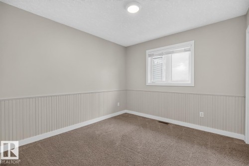 Room featuring neutral painted walls, wainscoting, and carpet flooring - 448 Ormsby Road W, Edmonton, AB 