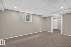 Spacious room featuring neutral carpeting, light-toned walls, and a drop ceiling with recessed lighting - 