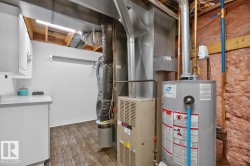 Dedicated utility area featuring a water heater, furnace, and stacked laundry appliances - 