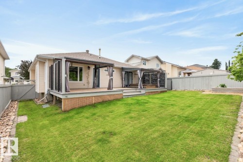 Expansive backyard featuring a manicured lawn, a multi-level deck with a pergola, exterior siding, and perimeter fencing - 448 Ormsby Road W, Edmonton, AB 