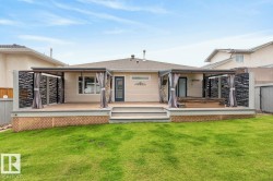 Rear exterior featuring a large elevated deck with steps to a grass lawn - 