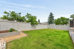 Expansive backyard featuring a manicured lawn, full-height privacy fencing, and a raised garden bed - 