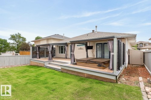 Expansive backyard featuring a multi-level deck, a built-in spa, and a covered patio area with privacy screens - 448 Ormsby Road W, Edmonton, AB 
