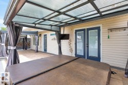 Outdoor covered patio featuring a hot tub, tiled flooring, and privacy screens - 