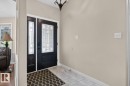 Entryway featuring a black paneled door with decorative glass, a coordinating sidelight, light neutral wall paint, and ceramic tile flooring - 448 Ormsby Road W, Edmonton, AB 