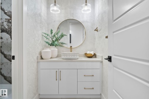 Bathroom vanity featuring a vessel sink, single-handle faucet, and round mirror with a gold-finish frame - 13152 187 Avenue, Edmonton, AB 