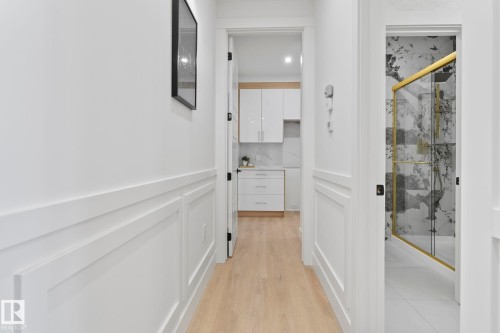 Hallway featuring light wood-finish flooring and white wainscoting - 13152 187 Avenue, Edmonton, AB 