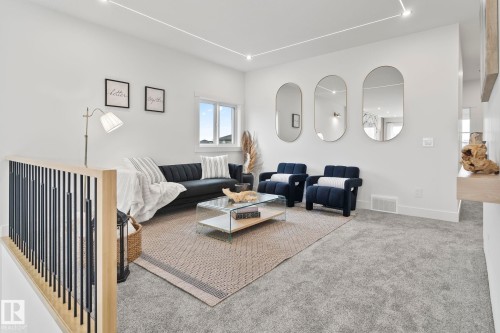 Open living area featuring light-toned carpeting and a contemporary railing with wood and black metal spindles - 13152 187 Avenue, Edmonton, AB 