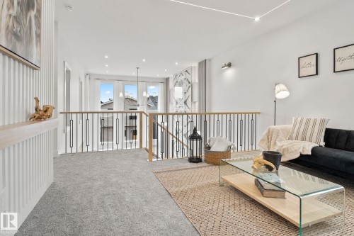 Open loft area featuring light gray carpet flooring and a contemporary railing with wood-finish handrails and black metal spindles - 13152 187 Avenue, Edmonton, AB 