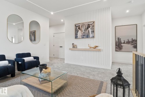Spacious upper-level landing featuring light gray carpeting, a contemporary glass coffee table with a wood-finish base, and a white paneled accent wall with a floating wood-finish shelf - 13152 187 Avenue, Edmonton, AB 