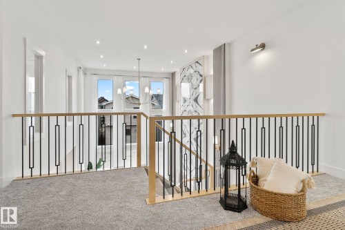 Upper-level landing featuring light gray carpeting, contemporary metal and wood-finish railing, recessed lighting, and wall-mounted sconces - 13152 187 Avenue, Edmonton, AB 
