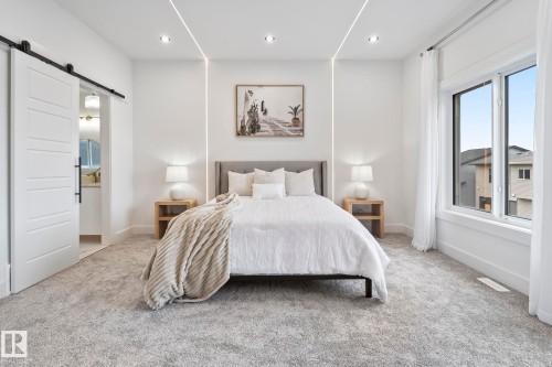 Spacious room featuring light gray carpeting, recessed ceiling lighting, and integrated linear wall lighting - 13152 187 Avenue, Edmonton, AB 