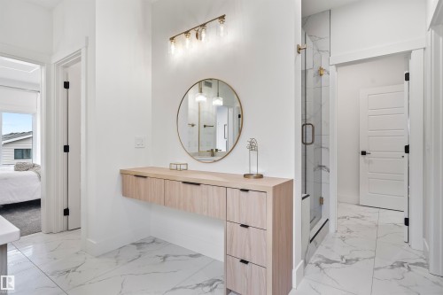 Floating wood-finish vanity with drawer storage, illuminated by a brass-finish light fixture - 13152 187 Avenue, Edmonton, AB 