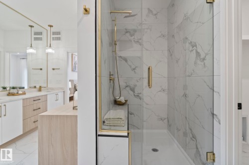 Spacious shower with large format marble-look tile, glass enclosure with gold-tone hardware, and built-in bench - 13152 187 Avenue, Edmonton, AB 