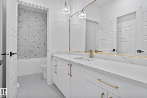 Double vanity featuring white cabinetry with gold-finish hardware, a single undermount sink, and a white countertop with subtle veining - 13152 187 Avenue, Edmonton, AB 