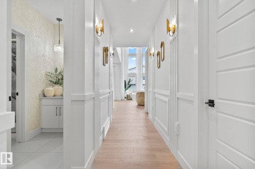 Hallway featuring wood-finish flooring, wainscoting, and modern wall sconces - 13152 187 Avenue, Edmonton, AB 