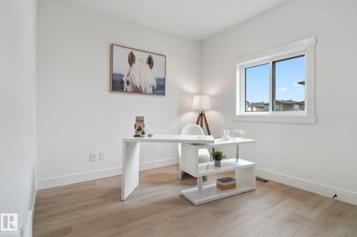 Bright interior space featuring light wood-finish flooring, white baseboards, and a single window with white trim - 13152 187 Avenue, Edmonton, AB 