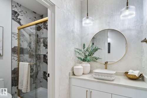 Bathroom featuring a gold-framed shower enclosure, large format marble-look tile, vessel sink, gold-toned fixtures, and pendant lighting - 13152 187 Avenue, Edmonton, AB 