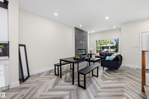 Open-concept living space with herringbone-patterned wood-finish flooring - 8319 81 Avenue Nw, Edmonton, AB 