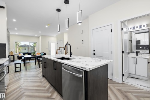 Central kitchen island featuring a waterfall-edge countertop and integrated stainless steel dishwasher - 8319 81 Avenue Nw, Edmonton, AB 