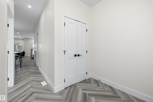 Herringbone-patterned wood-finish flooring extending through a brightly lit hallway - 8319 81 Avenue Nw, Edmonton, AB 