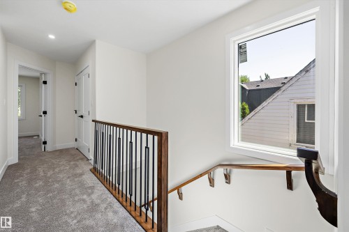Upper-level hallway featuring plush gray carpeting, recessed lighting, white walls, and a large window - 8319 81 Avenue Nw, Edmonton, AB 