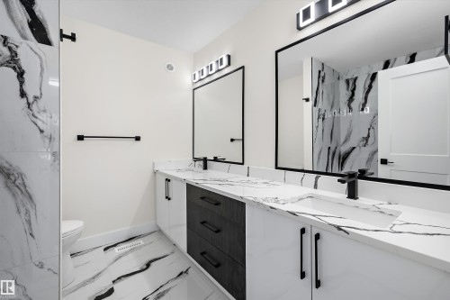 Bathroom featuring a dual vanity with integrated sinks and black hardware, framed mirrors, and contemporary lighting - 8319 81 Avenue Nw, Edmonton, AB 