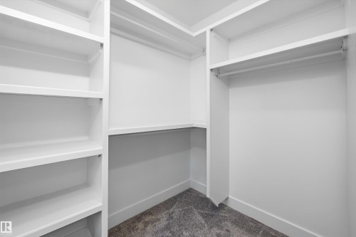 Custom closet system featuring white built-in shelving, hanging rods, and corner storage - 8319 81 Avenue Nw, Edmonton, AB 