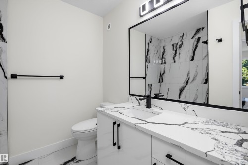 Modern bathroom featuring a vanity with a white countertop and black veining, a rectangular undermount sink, and matte black hardware - 8319 81 Avenue Nw, Edmonton, AB 