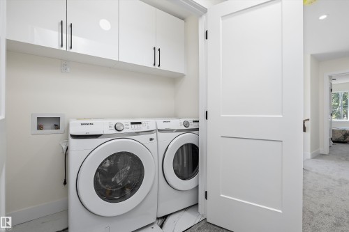 Dedicated laundry area featuring white cabinetry with black hardware, white baseboards, and a paneled white door - 8319 81 Avenue Nw, Edmonton, AB 