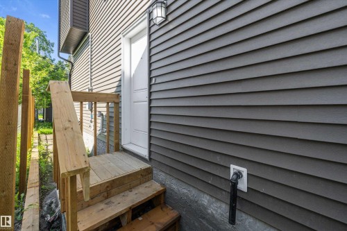 Side entry featuring wood stairs and railing - 8319 81 Avenue Nw, Edmonton, AB 