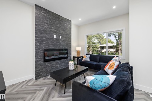 Living area featuring a floor-to-ceiling slate-style accent wall with an integrated linear fireplace - 8319 81 Avenue Nw, Edmonton, AB 