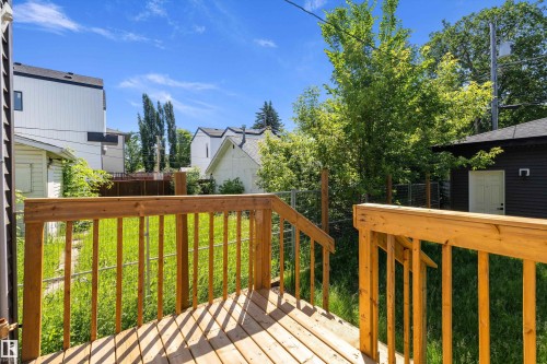 Wooden deck featuring a railing and steps, overlooking a grassy yard with mature trees - 8319 81 Avenue Nw, Edmonton, AB 