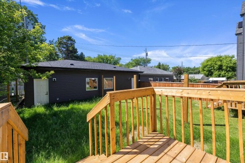 Expansive outdoor deck with natural wood railing overlooking a grassy yard - 8319 81 Avenue Nw, Edmonton, AB 