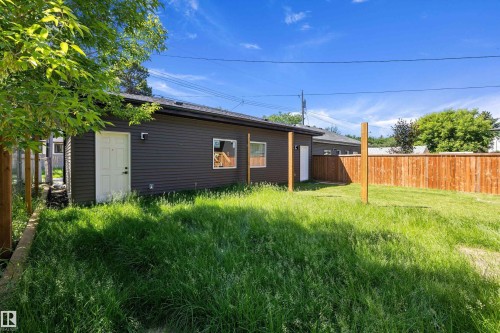 Rear exterior featuring dark siding, a white entry door, and a new privacy fence - 8319 81 Avenue Nw, Edmonton, AB 