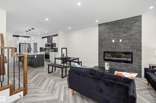 Open-concept living space featuring a floor-to-ceiling slate-style accent wall with an inset electric fireplace - 8319 81 Avenue Nw, Edmonton, AB 