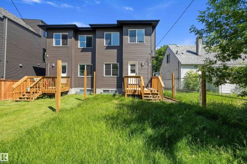 Rear exterior with horizontal siding, multiple windows, and two separate wooden decks - 8319 81 Avenue Nw, Edmonton, AB 