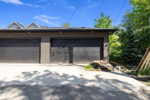 Two-car garage featuring dark paneled doors and horizontal siding accents - 8319 81 Avenue Nw, Edmonton, AB 